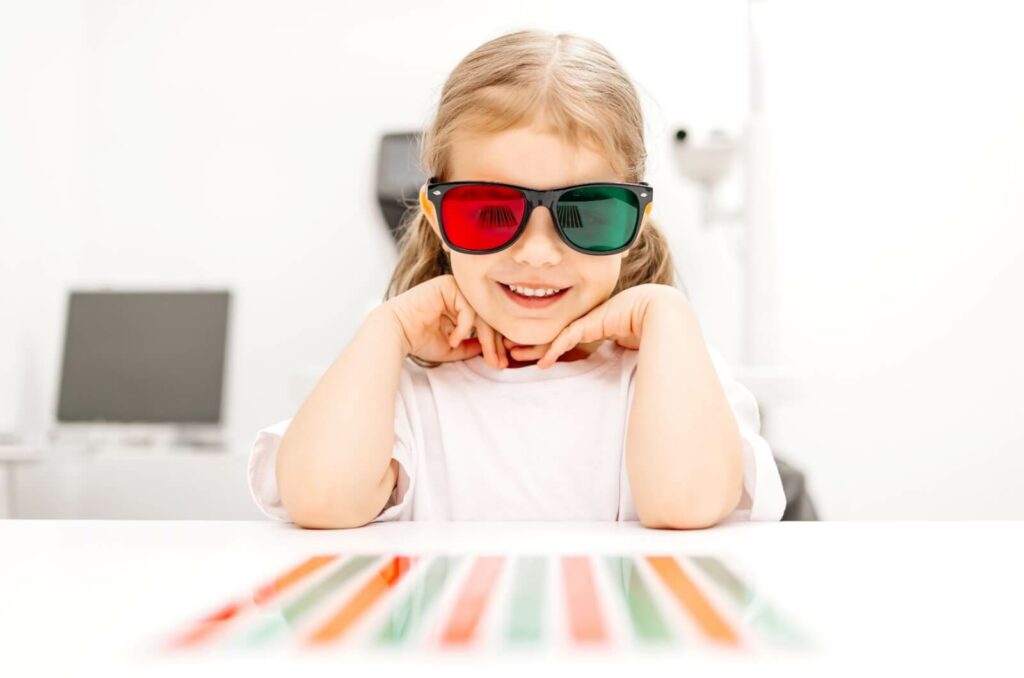 A child wears specialized green and red colored glasses during their visual therapy session.