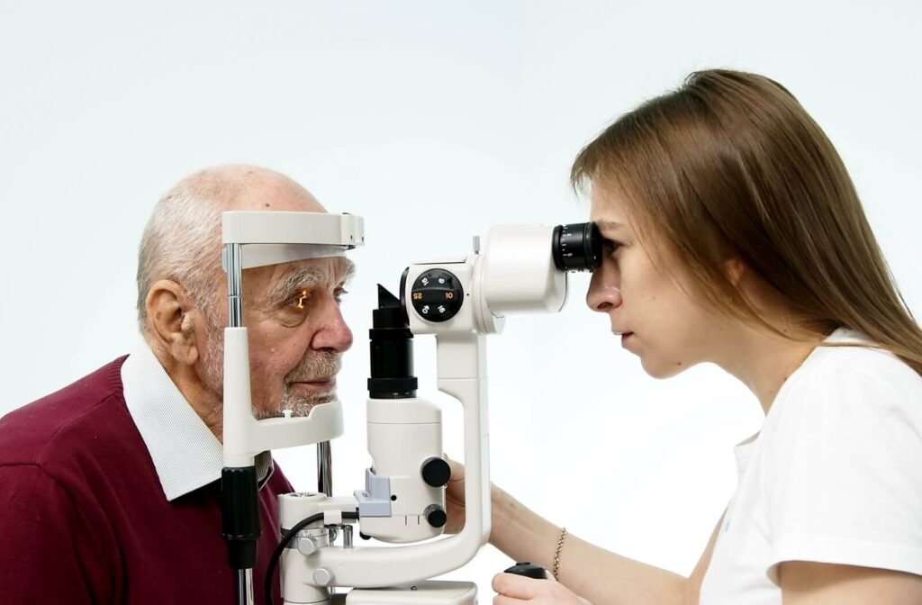 An optometrist uses a slit lamp to inspect their senior patient's retina for signs of diabetic retinopathy.