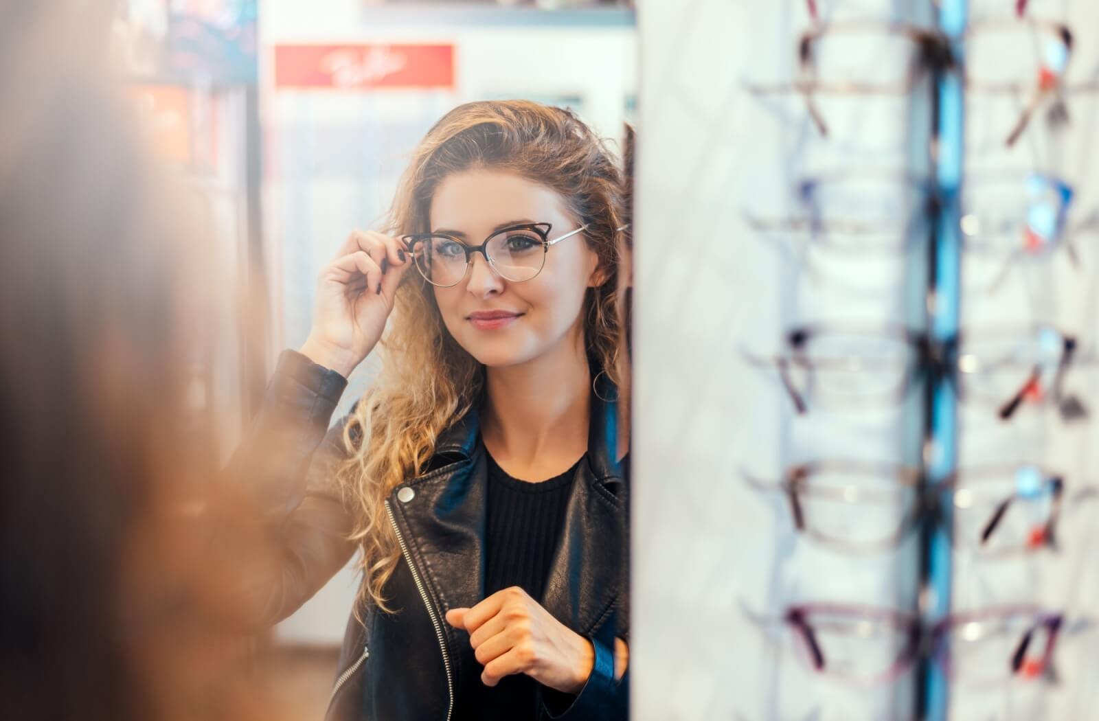 A person checking out the eyeglass through the mirror